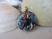 Pendentif bouton rond en pâte polymère avec motif de spirales multicolores sur fond noir et cabochon rond noir mat