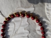Collier en perles de verre rouge laquées à motifs et perles gouttes de métal doré. 45 cm.