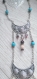 Un sautoir avec des pendentifs styles égyptien et un autre pendentif vers le haut en métal argenté qui fait croire à un deuxième collier le tout avec des perles pour toute la beauté 