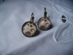 Boucles d'oreilles dormeuses bords ciseles en metal couleur bronze   image sous dome en verre bombe 14 mm collection les dentelles