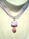 Pendentif constitué d'une perle rectangulaire en pâte fimo, à motif vitrail rose, violet et blanc avec une perle en verre rose suspendue.
