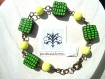 Bracelet taille m constitué de 4 perles carrées plates, en pâte fimo, au motif carré vert et noir, entourées d'anneaux bronze et de perles en verre vertes / jaune anis.