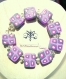 Bracelet taille s/m constitué de 9 perles carrées plates, en pâte fimo, au motif original gris métallisé, violet, rose fuchsia et blanc.