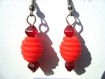 Boucles d'oreilles composées d'une perle ovale en forme de ruche, en pâte fimo rouge, entourée de perles en verre toupies rouges.