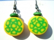 Boucles d'oreilles composées d'une perle ronde plate, en pâte fimo, à motif fleur verte et jaune, avec une rondelle en bois verte au dessus.