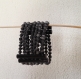 Manchette en perles de papier noir, en papier recyclé ;  circonférence 19cm, hauteur 5.5cm
