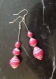 Boucles d’oreille pendantes en perles de papier recyclé fuchsia.