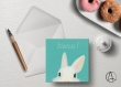 Carte postale « lapinou » illustrée d’un bébé lapin blanc sur fond vert pastel et texte 