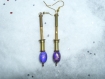 Boucles d'oreilles uniques avec tiges dorées et une perle violette ovale 