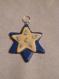Pendentif en fimo étoile jaune avec des petit bonhomme de neige sur une étoile bleu foncé 