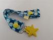 Attache-tétine en tissus à motifs géométriques bleus, gris et jaunes avec pression et attache type bretelle étoile 