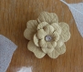 Fleur simili cuir couleur beige avec un strass. 